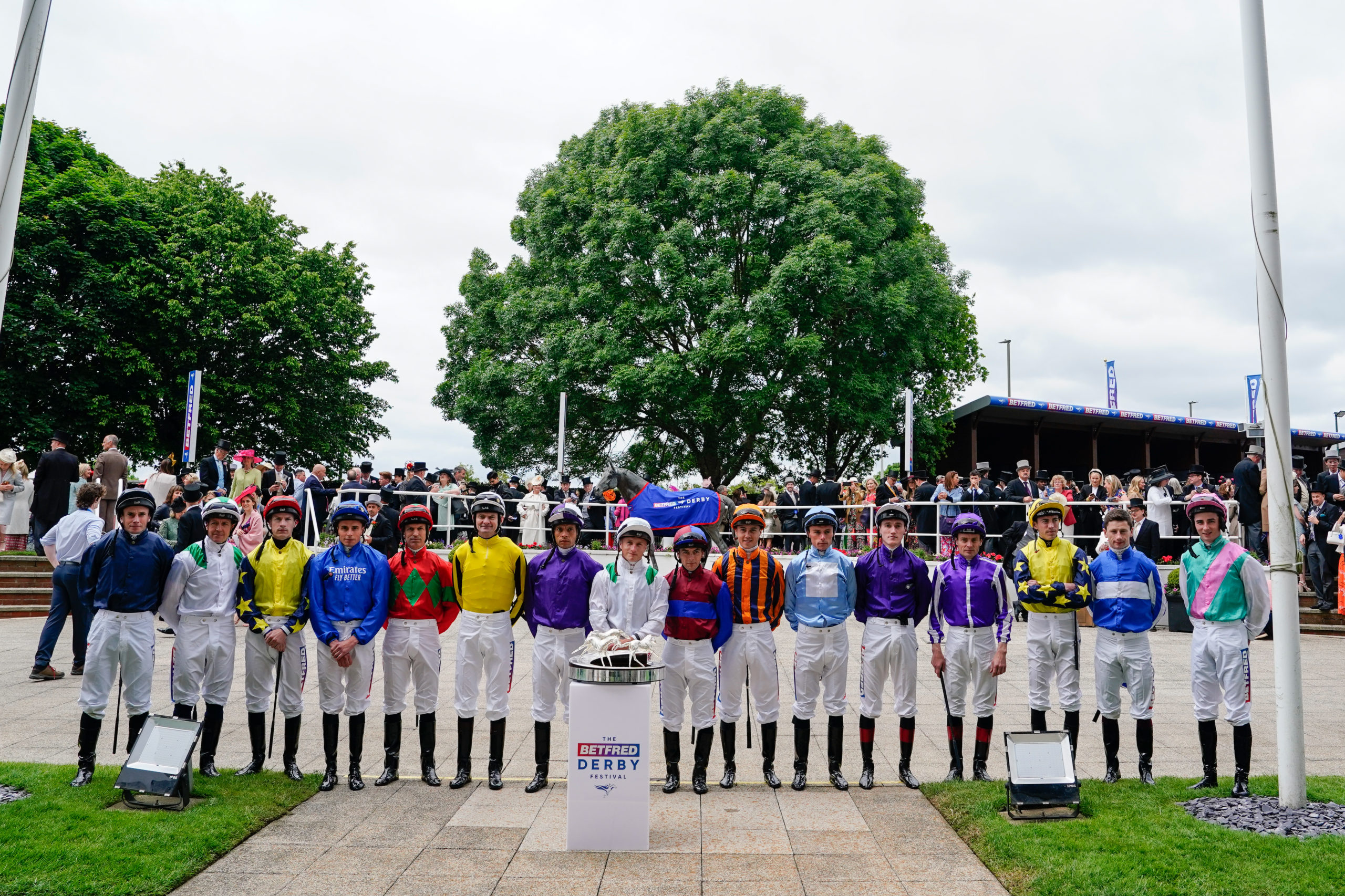 Todos los jockeys de la carrera, formando delante del Queen’s Stand y junto a la estatua de Generous